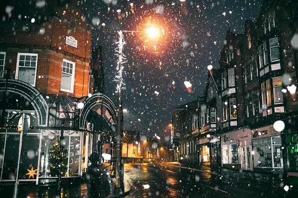 Evening winter shot of a London street with snow falling.